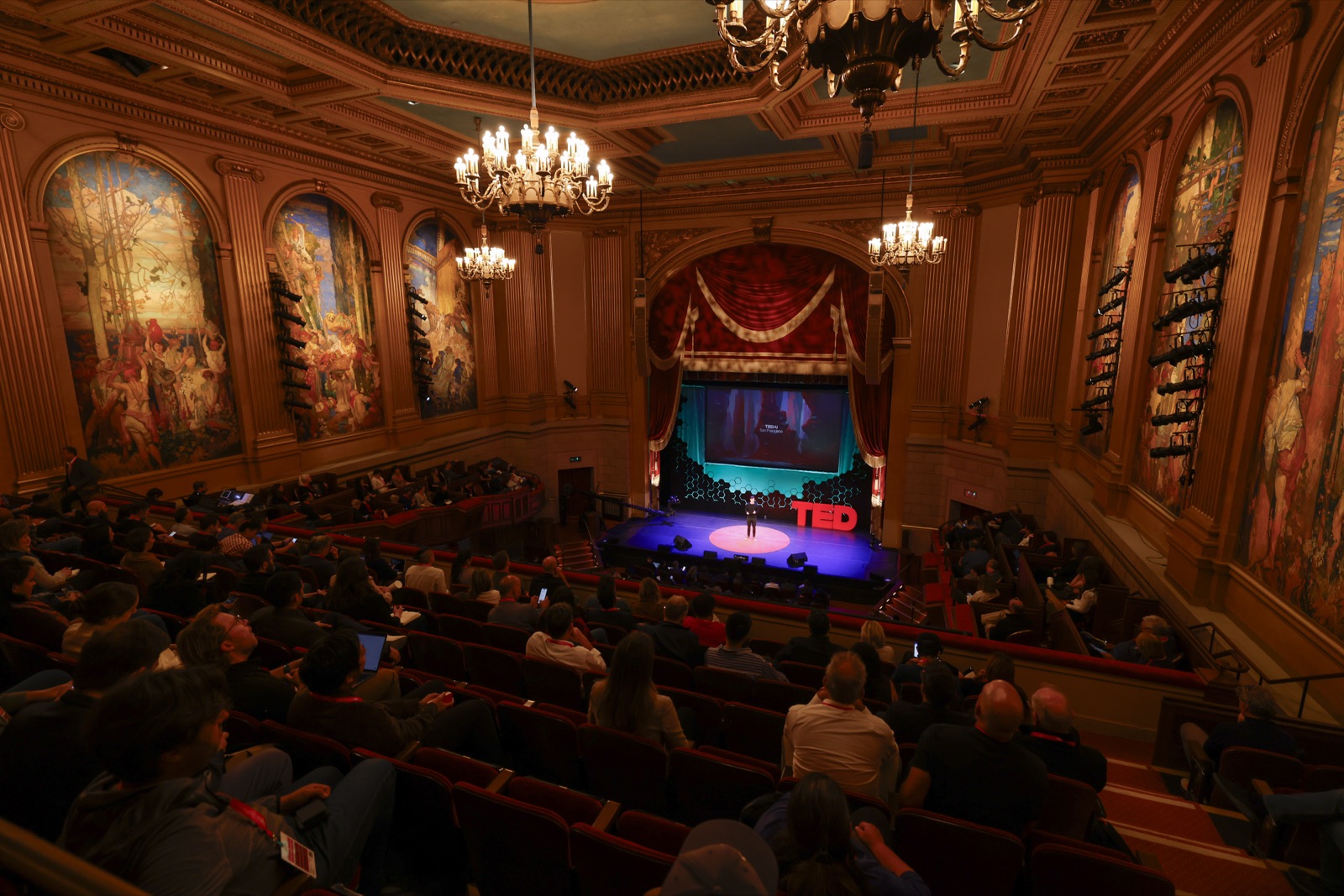 TED AI main stage seen from the balcony of an ornate theater with murals and chandeliers