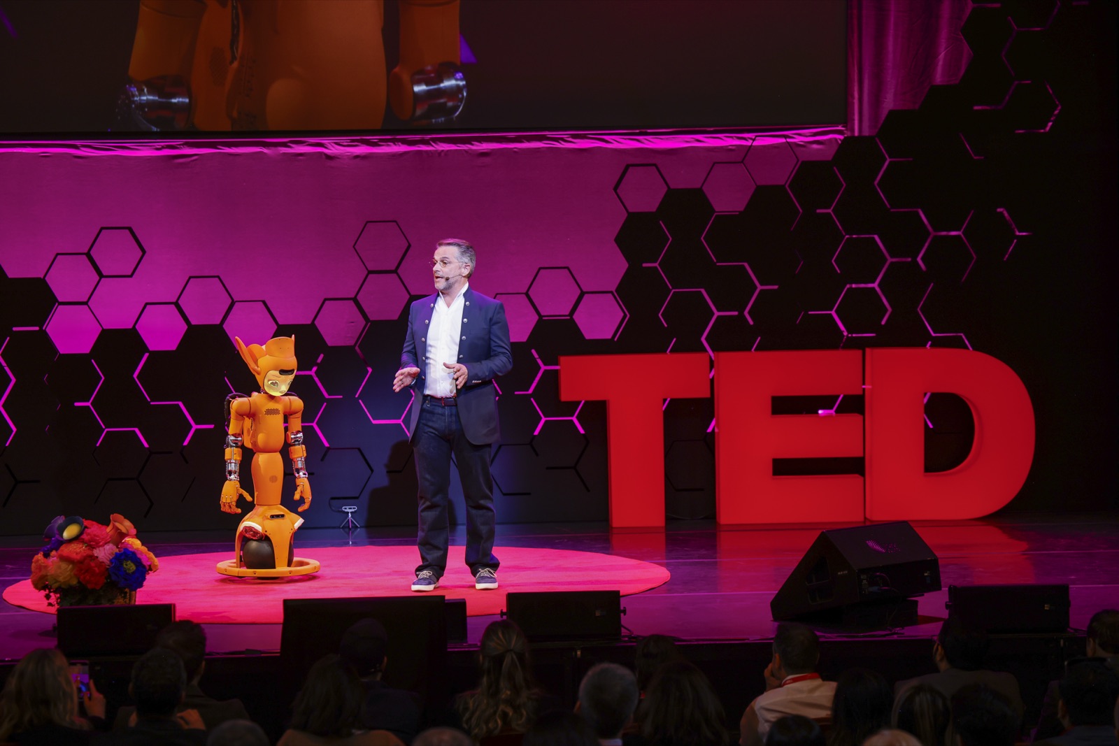 Speaker on stage with a humanoid robot at TED AI